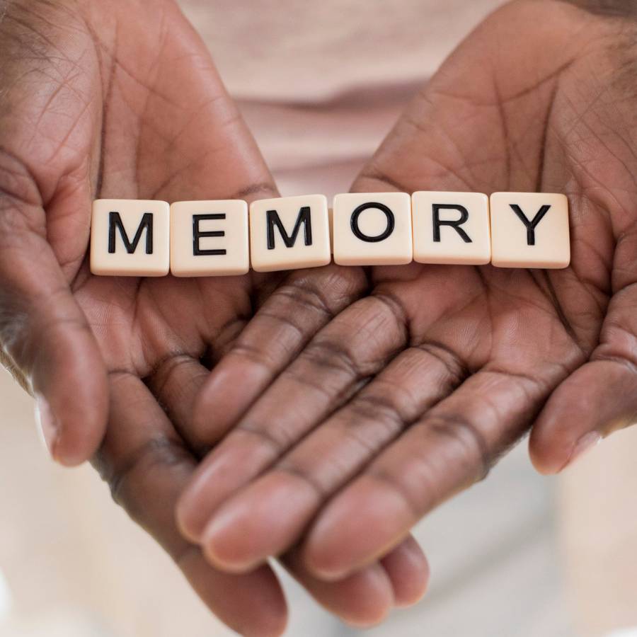 Scrabble letter tiles in the palm of a person's hand that spell out "memory"